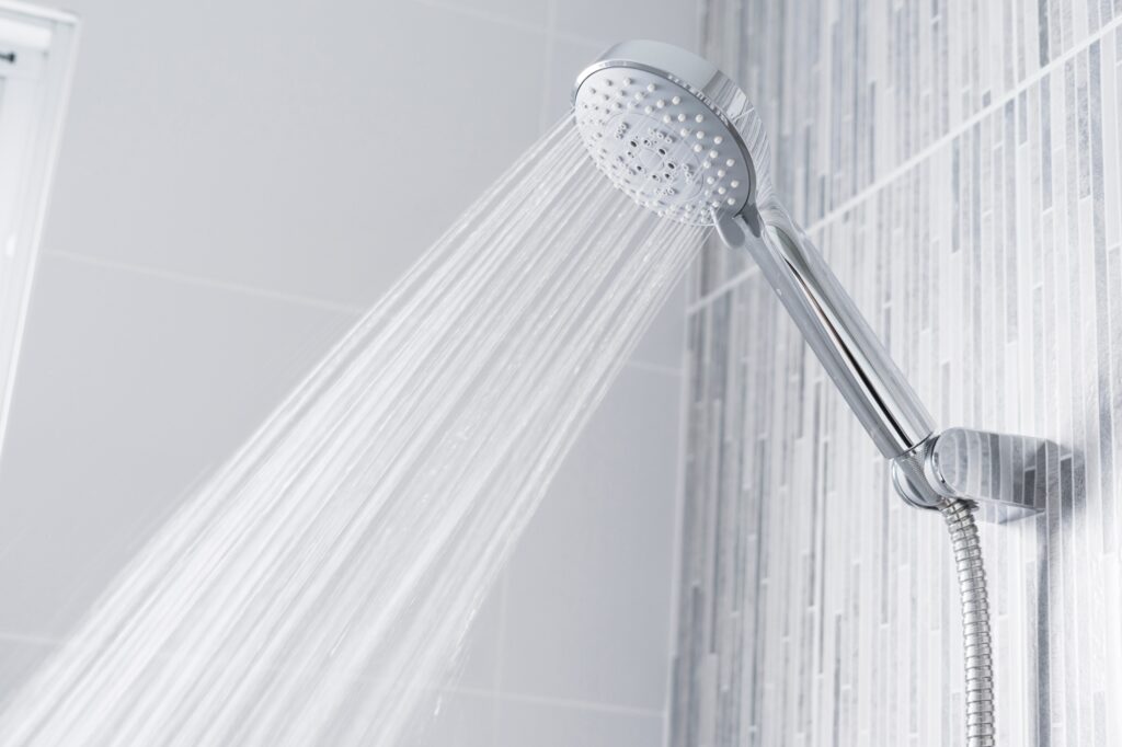 Handheld showerhead mounted on a bathroom wall spraying water